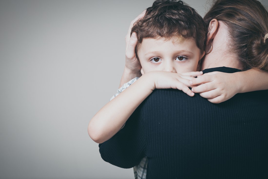 young child looking over mothers shoulder